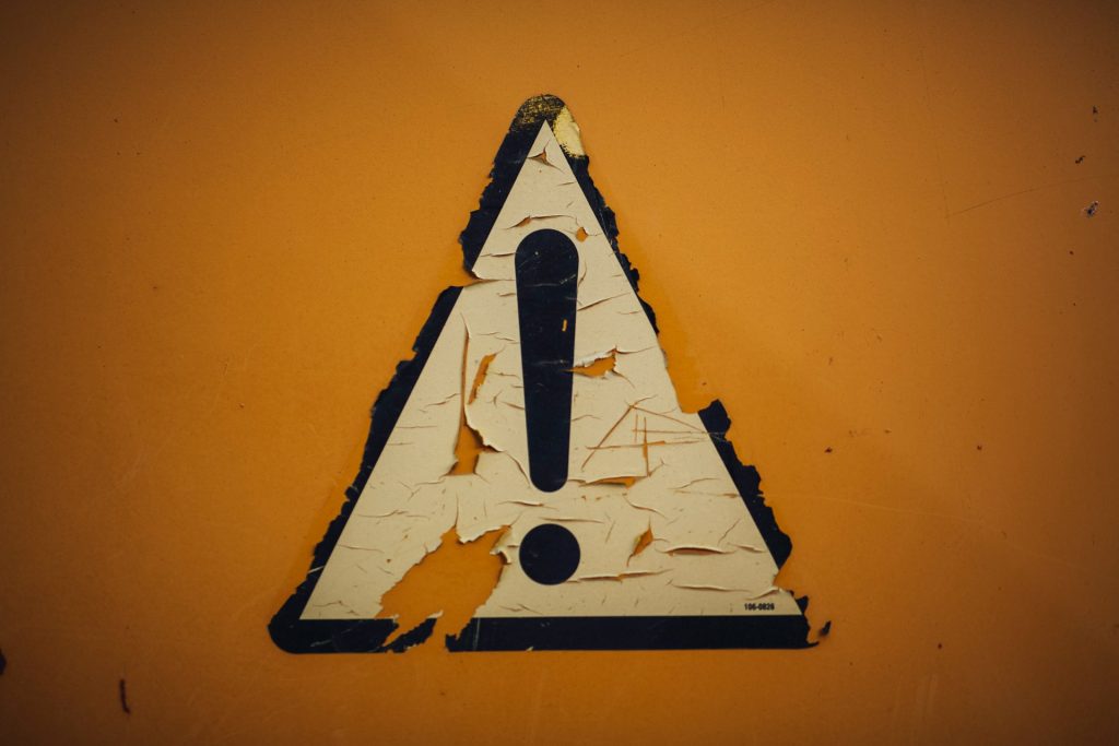 Rusty metal iron weathered sticker "caution" ! by Markus Spiske