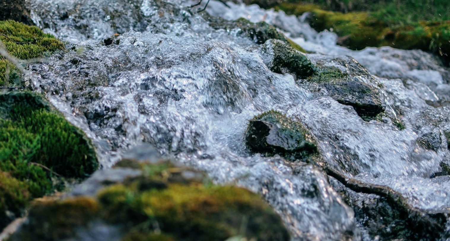 Water flowing over a rock, credit to ezra-jeffrey